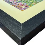 summer at the needles, the corner of a print in a black frame by Isle of Wight artist Julia Tanner