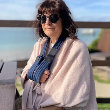 Julia Tanner art sitting in the sunshine with a sling supporting her fractured shoulder