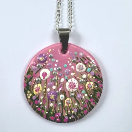 a pink hand painted round necklace with a flower meadow by Isle of Wight artist Julia Tanner